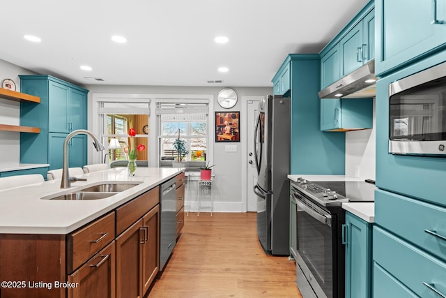 kitchen featuring visible vents, a sink, light countertops, under cabinet range hood, and stainless steel appliances