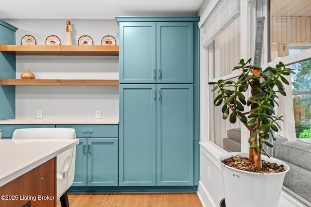 kitchen featuring light countertops, light wood-style flooring, open shelves, and blue cabinets