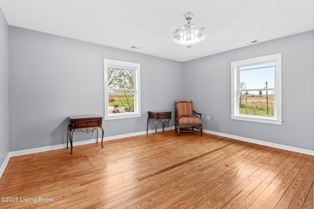 unfurnished room featuring light wood-style floors, visible vents, and baseboards