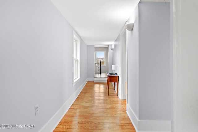 hall featuring baseboards and light wood-type flooring
