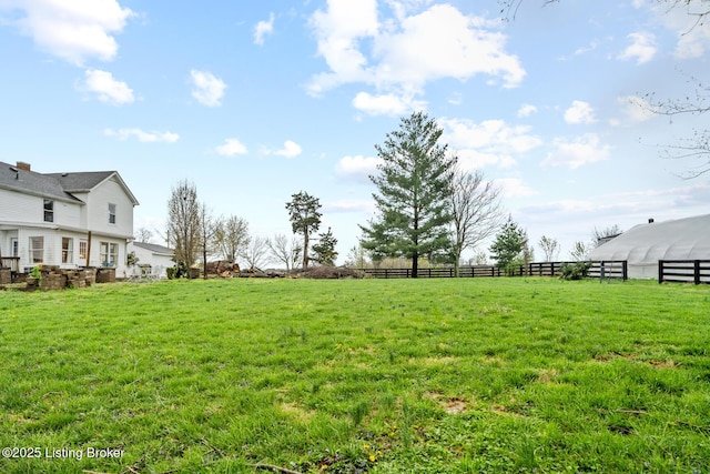 view of yard featuring a rural view, fence, and an outbuilding