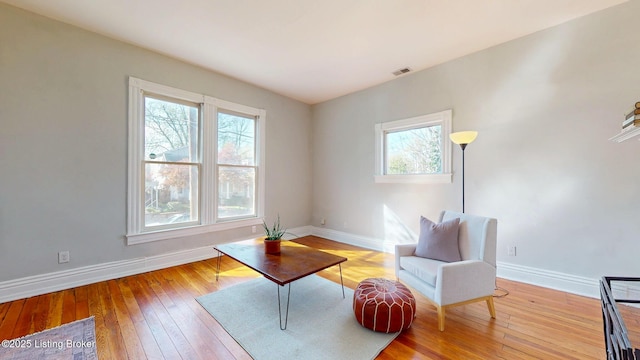 living area featuring visible vents, baseboards, and wood-type flooring