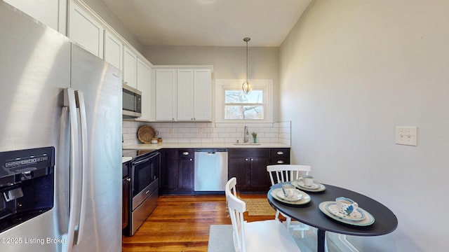 kitchen featuring tasteful backsplash, light countertops, appliances with stainless steel finishes, a sink, and wood finished floors