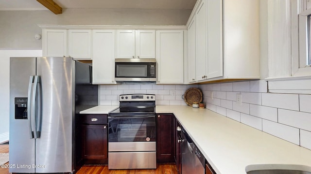 kitchen with white cabinetry, wood finished floors, light countertops, stainless steel appliances, and backsplash