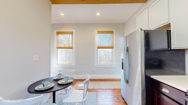 kitchen featuring stainless steel fridge with ice dispenser, light countertops, light wood finished floors, and white cabinetry