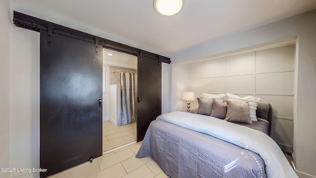 bedroom with a barn door and light tile patterned flooring