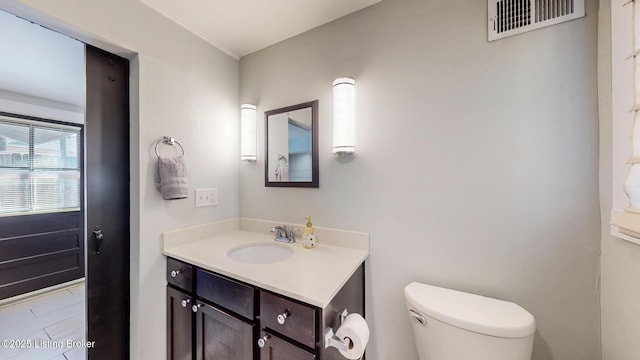 bathroom featuring toilet, vanity, and visible vents