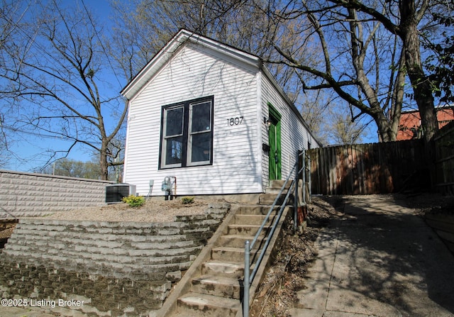 view of home's exterior with central AC unit, fence, and stairway
