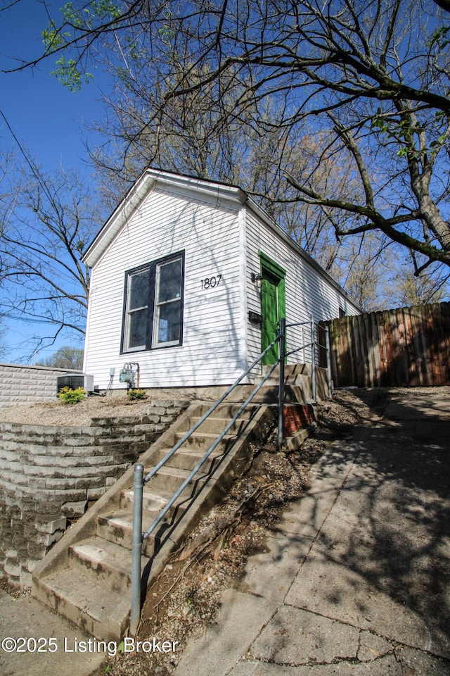 view of side of property with central AC and fence