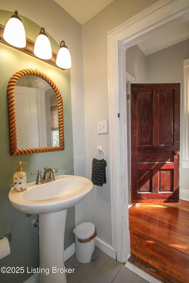 bathroom featuring baseboards, a sink, and wood finished floors