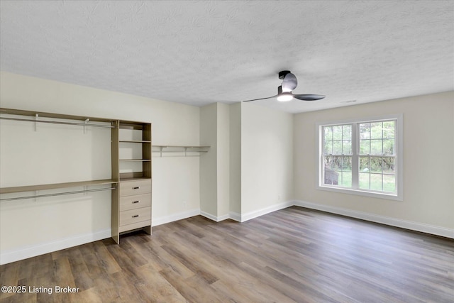 unfurnished bedroom featuring baseboards, dark wood-style floors, a textured ceiling, and ceiling fan