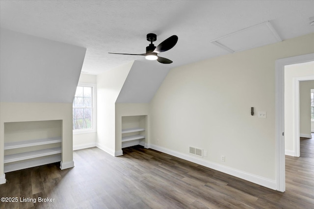 additional living space featuring baseboards, visible vents, built in shelves, wood finished floors, and ceiling fan