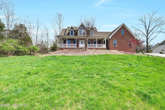 rear view of property featuring brick siding, a yard, and covered porch