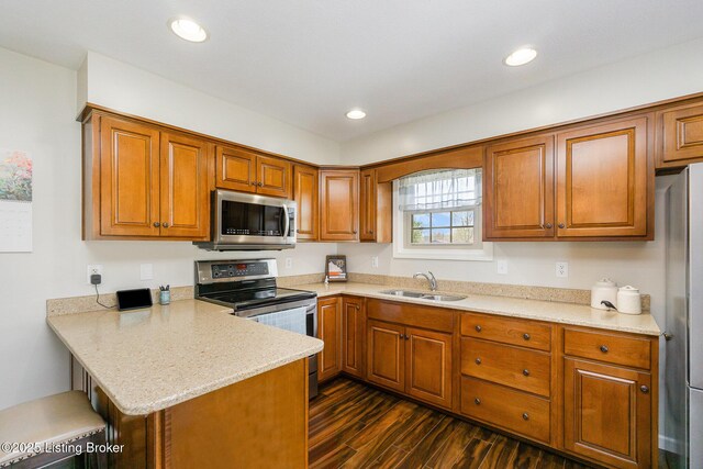kitchen featuring a peninsula, a sink, brown cabinets, and appliances with stainless steel finishes