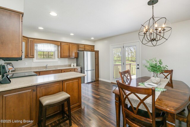 kitchen with a sink, brown cabinetry, a chandelier, dark wood finished floors, and freestanding refrigerator