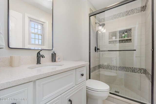 bathroom featuring toilet, vanity, and a stall shower
