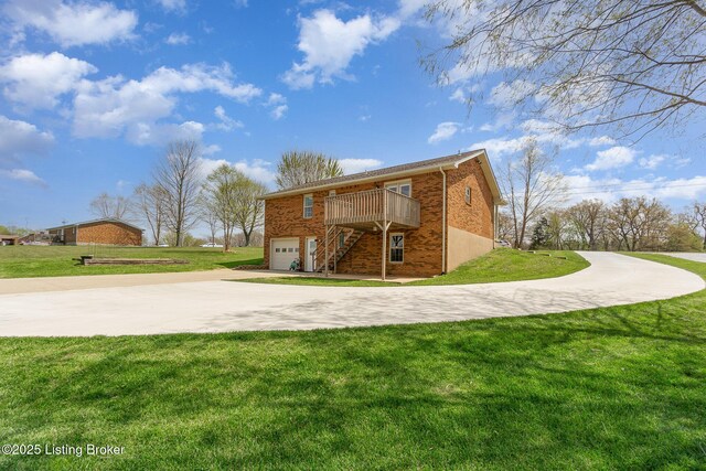 rear view of house with concrete driveway, brick siding, an attached garage, a lawn, and stairs