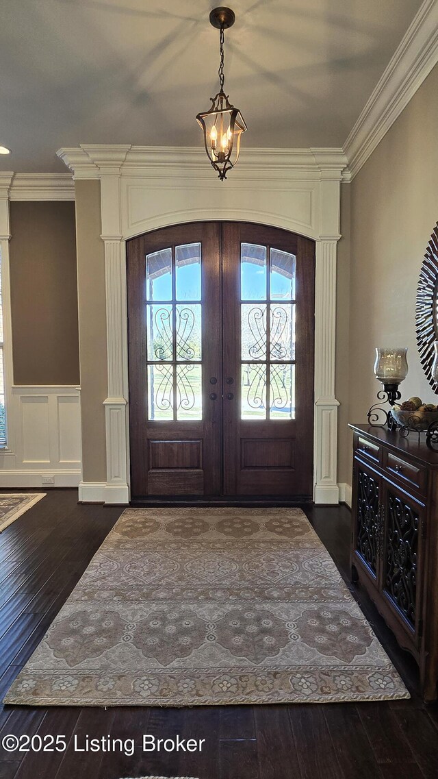 entrance foyer featuring dark wood-type flooring, crown molding, french doors, and wainscoting