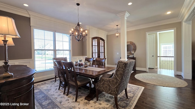 dining room with a notable chandelier, a decorative wall, dark wood-style floors, crown molding, and wainscoting