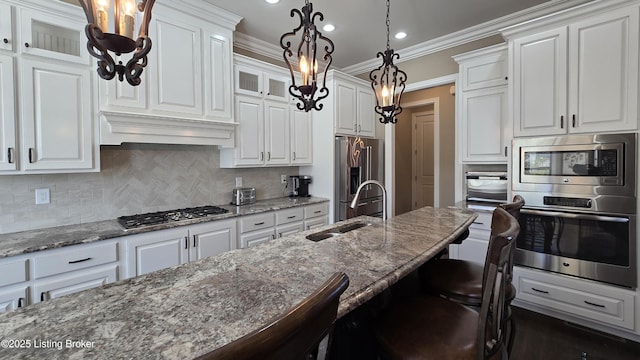 kitchen featuring custom range hood, white cabinets, a kitchen bar, appliances with stainless steel finishes, and a sink