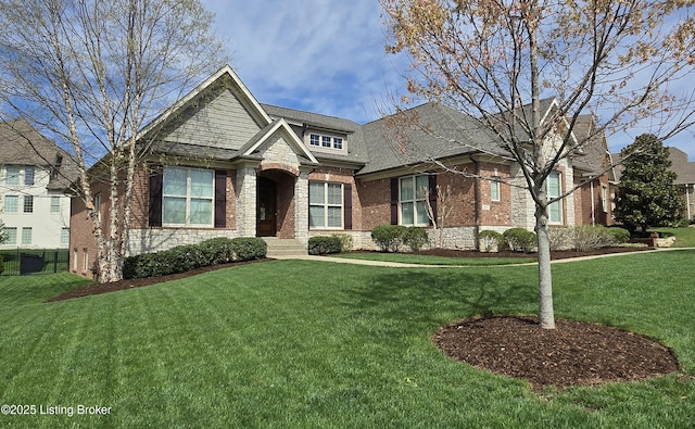 craftsman-style home with a front yard, brick siding, and stone siding