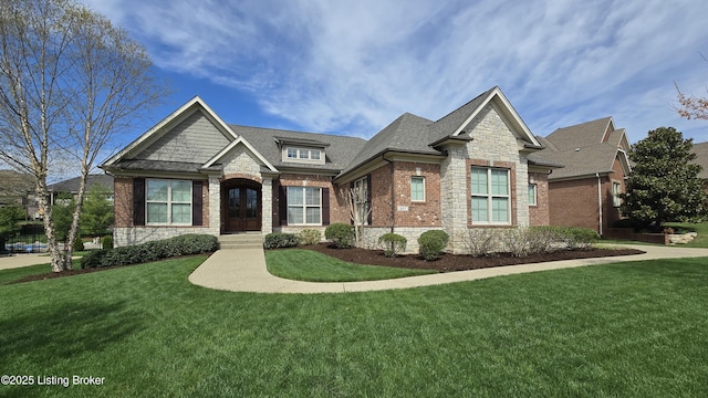 craftsman-style home with roof with shingles, stone siding, a front lawn, and brick siding