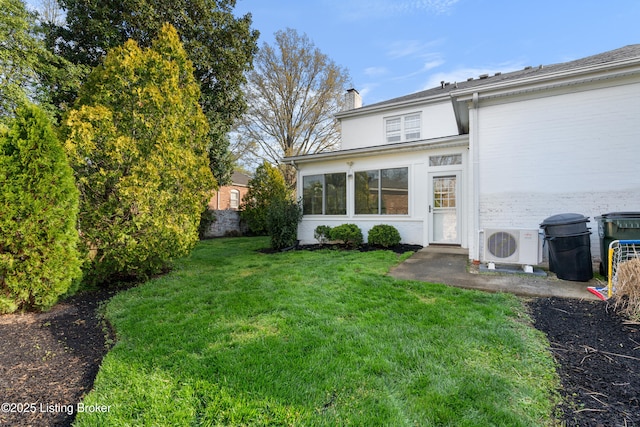 back of property featuring a yard, ac unit, and a chimney