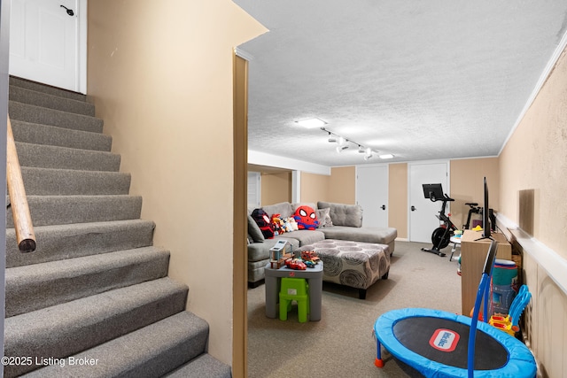 game room featuring rail lighting, carpet flooring, and a textured ceiling