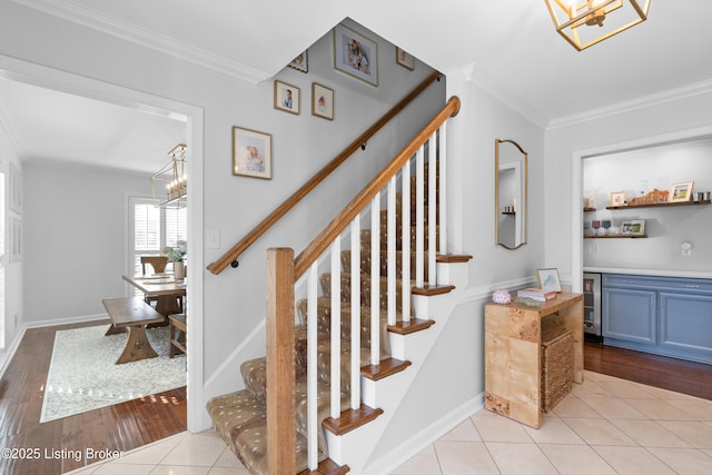 staircase with ornamental molding, baseboards, an inviting chandelier, and wood finished floors