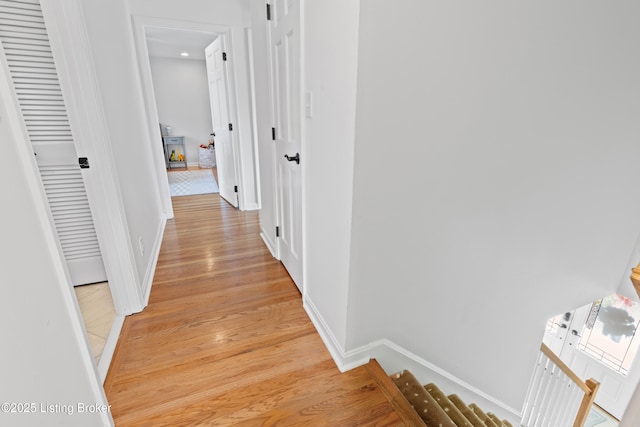 corridor with stairway, light wood-type flooring, and baseboards