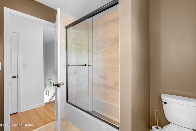 bathroom featuring bath / shower combo with glass door, toilet, and wood finished floors