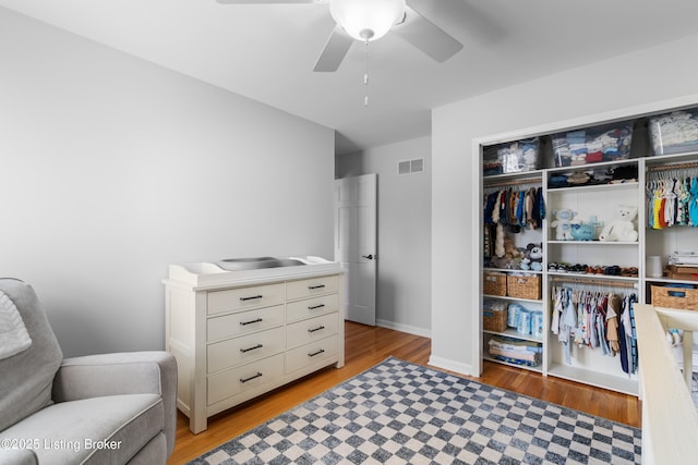 interior space with light wood-type flooring, a closet, a ceiling fan, visible vents, and baseboards