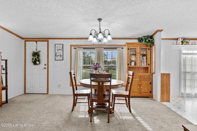 dining area featuring a textured ceiling, an inviting chandelier, ornamental molding, and carpet floors