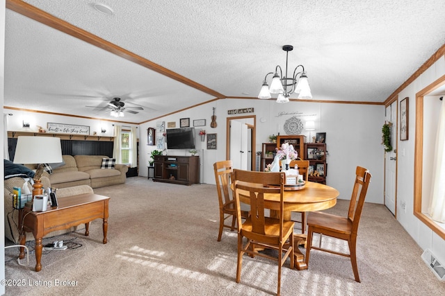 dining area featuring light carpet, a textured ceiling, ornamental molding, and ceiling fan with notable chandelier