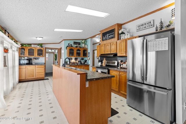 kitchen with crown molding, light floors, dark countertops, a sink, and stainless steel appliances