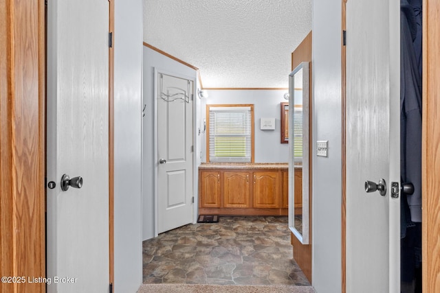 bathroom featuring stone finish floor, a textured ceiling, and crown molding