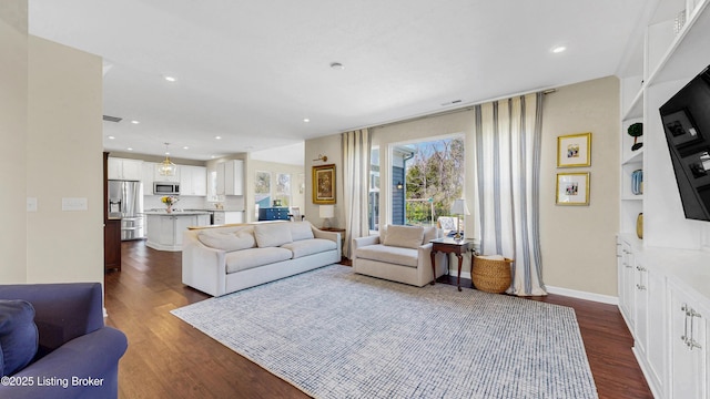 living room with baseboards, built in features, recessed lighting, and dark wood finished floors