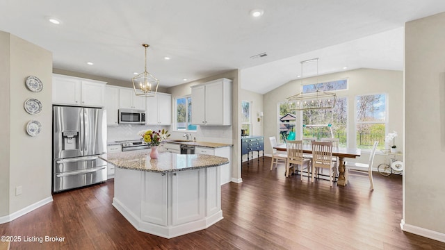 kitchen featuring light stone counters, a chandelier, appliances with stainless steel finishes, and dark wood finished floors