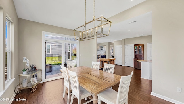 dining room featuring dark wood finished floors, visible vents, baseboards, and a notable chandelier