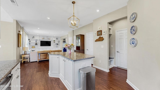 kitchen featuring dark wood finished floors, a notable chandelier, light stone counters, pendant lighting, and white cabinetry