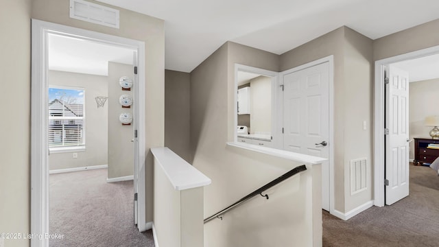 corridor with carpet, visible vents, and baseboards