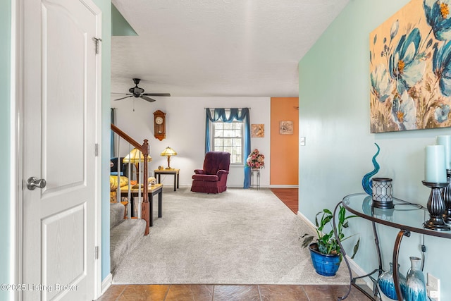 living area featuring baseboards, carpet flooring, a textured ceiling, stairs, and ceiling fan