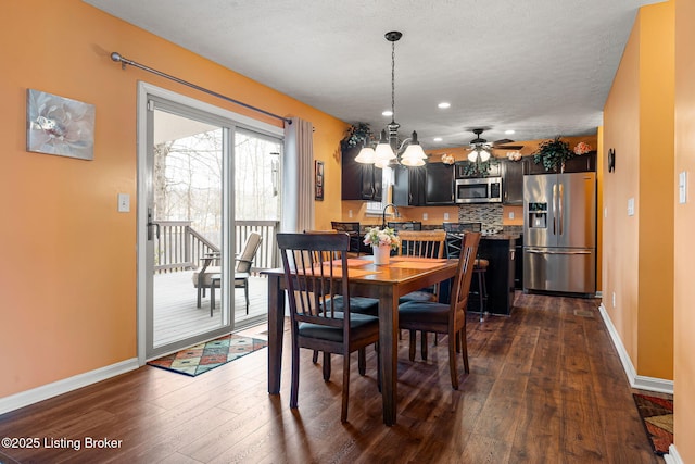 dining area with dark wood-style flooring, baseboards, a textured ceiling, and ceiling fan with notable chandelier