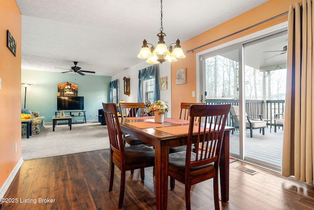 dining room with ceiling fan with notable chandelier, a textured ceiling, visible vents, dark wood-style flooring, and baseboards