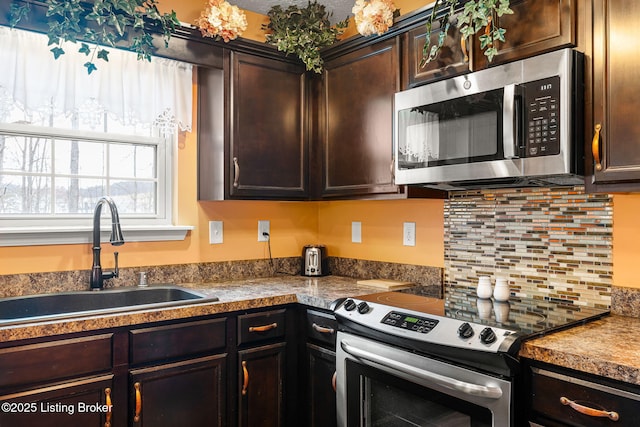 kitchen with a sink, tasteful backsplash, dark brown cabinetry, and stainless steel appliances