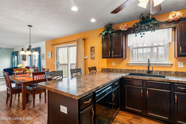 kitchen with black dishwasher, a sink, a peninsula, and dark countertops