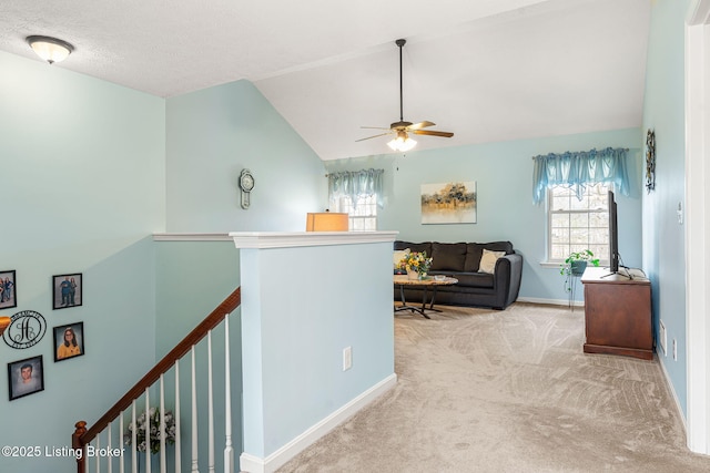corridor with an upstairs landing, baseboards, lofted ceiling, and carpet