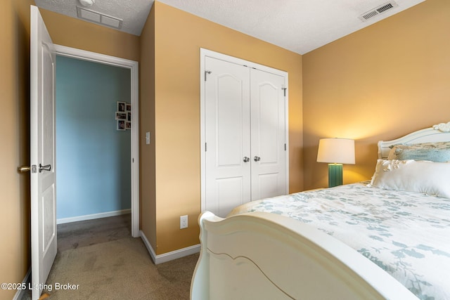 carpeted bedroom with visible vents, a closet, and a textured ceiling