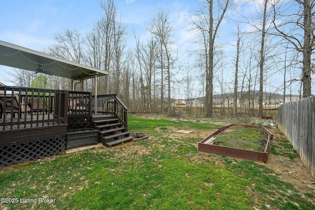view of yard with a garden, a wooden deck, and fence