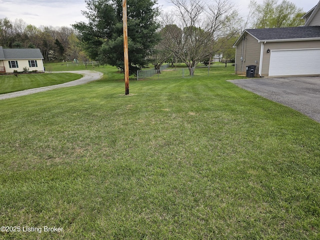 view of yard with fence, driveway, and a garage
